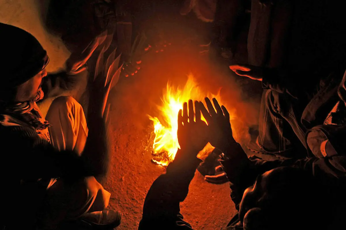 Indian people warm themselves near a bonfire in a slum area in Siliguri on January 11, 2011. As thousands of homeless people sought places in temporary shelters, more than 80 people were reported to have died due to the cold weather in Uttar Pradesh, Indi