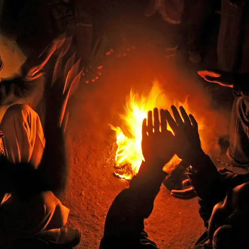 Indian people warm themselves near a bonfire in a slum area in Siliguri on January 11, 2011. As thousands of homeless people sought places in temporary shelters, more than 80 people were reported to have died due to the cold weather in Uttar Pradesh, Indi