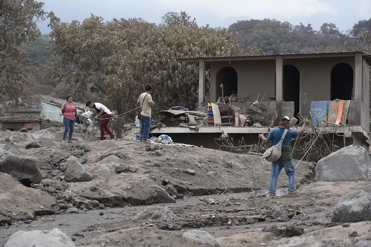 GU106. SAN MIGUEL DE LOS LOTES (GUATEMALA), 07/06/2018.- Un grupo de personas retira los escombros de las viviendas parcialmente enterradas debido a la erupción del Volcán de Fuego el pasado domingo, en un intento por encontrar a algunos de sus familiares