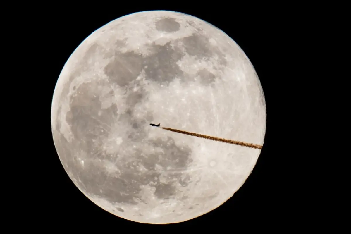 A plane flies past the full moon in Nuremberg, on February 19, 2019. (Photo by Daniel Karmann / dpa / AFP) / Germany OUT