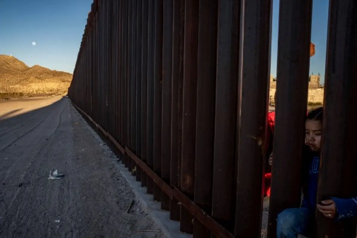 (FILES) In this file photo taken on March 19, 2019 A young Mexican girl is pictured on the between the metal fencing on the US-Mexico border in Anapra, New Mexico. - The Supreme Court said on July 26, 2019 that US President Donald Trump can proceed with a