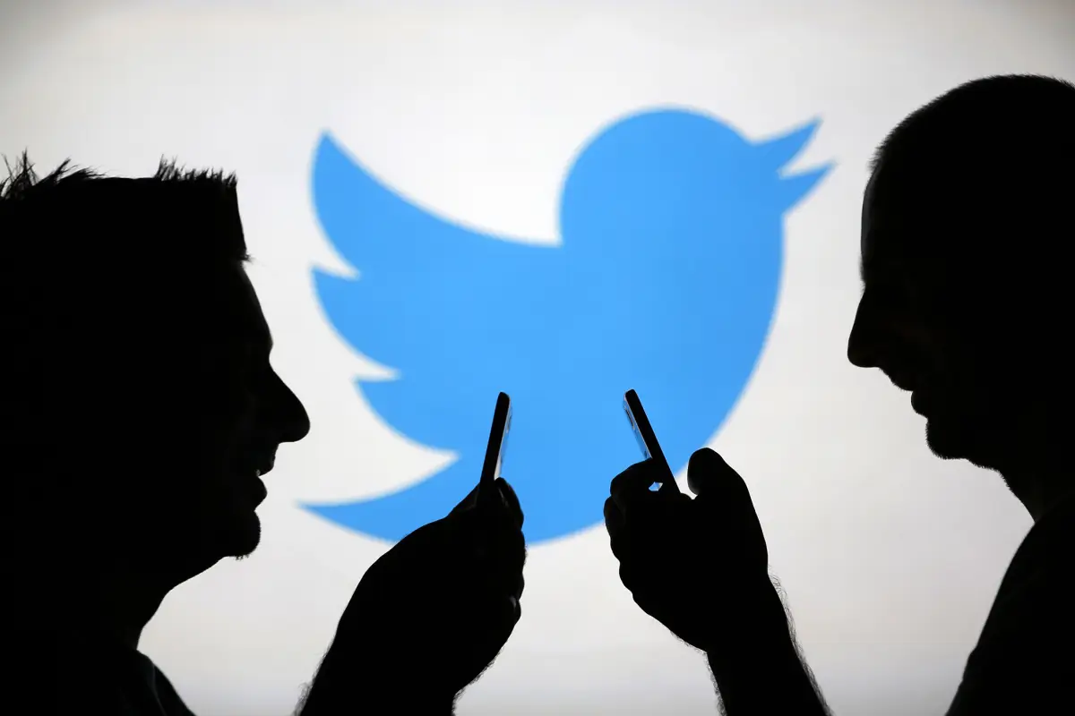 Image: Men are silhouetted against a video screen with an Twitter logo as he poses with an Samsung S4 smartphone in this photo illustration taken in the central Bosnian town of Zenica, 