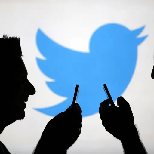 Image: Men are silhouetted against a video screen with an Twitter logo as he poses with an Samsung S4 smartphone in this photo illustration taken in the central Bosnian town of Zenica ,