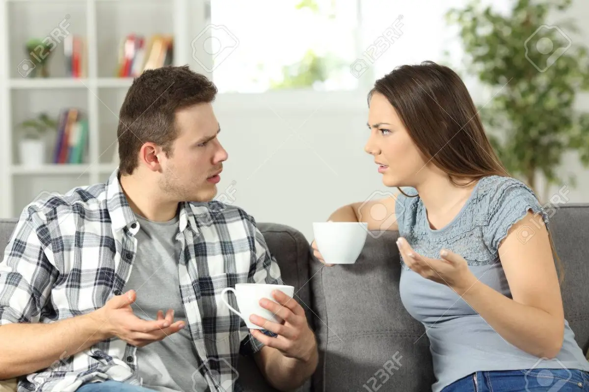 Angry couple arguing sitting on a couch at home