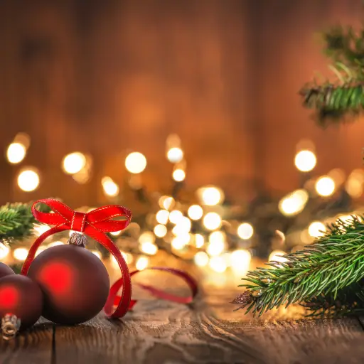 Red Christmas Ornaments on Wood Background and defocused lights. Spruce Tree branch on the left and right.