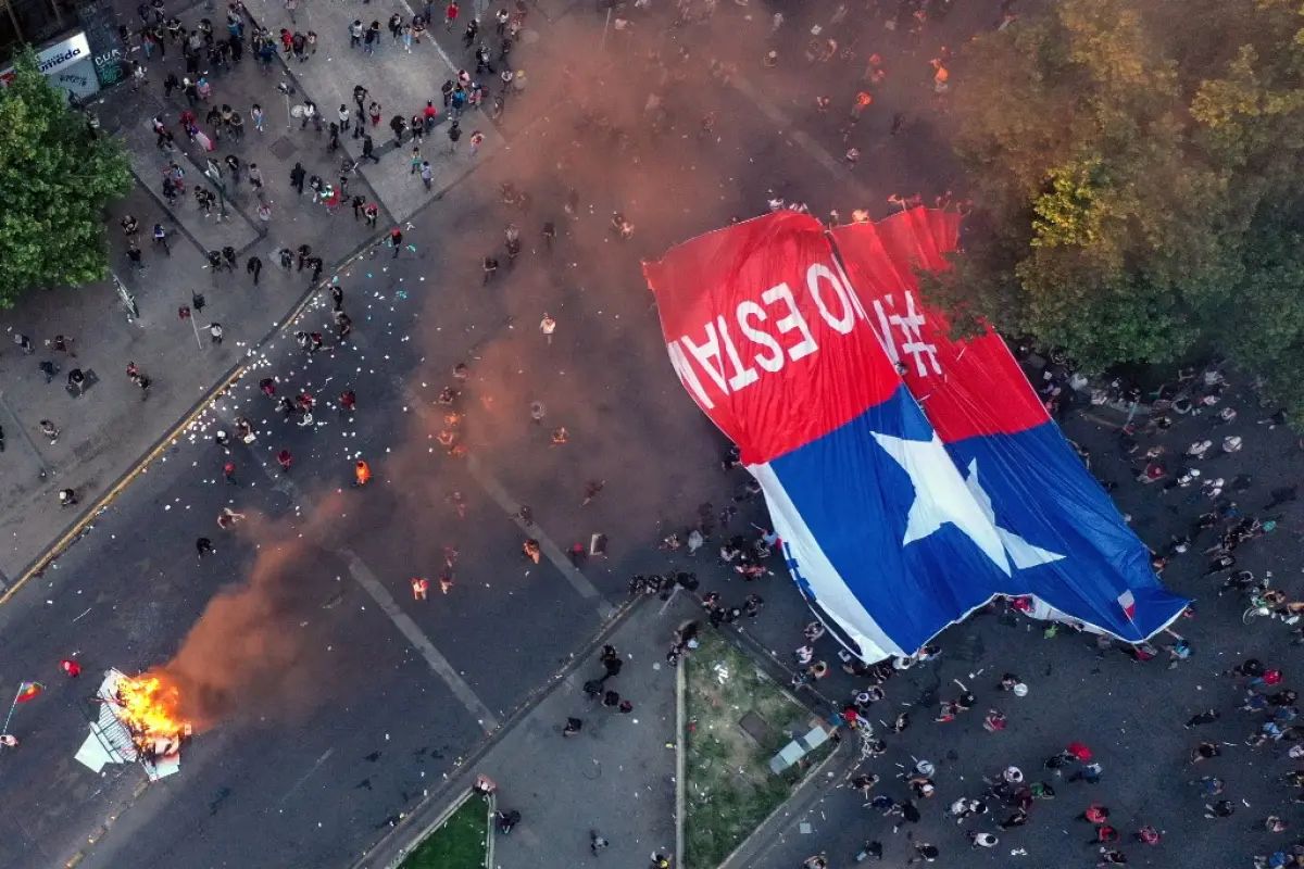 Aerial view of people demonstrating with a torn Chilean national flag in Santiago, on October 25, 2019, a week after violent protests started. - Demonstrations against a hike in metro ticket prices in Chile's capital exploded into violence on October 18, 