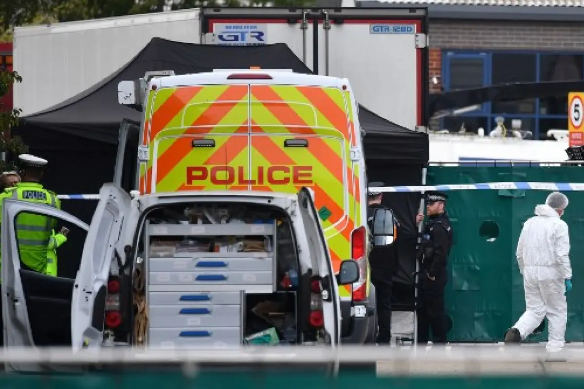 British Police officers in forsensic suits work near a lorry, believed to have originated from Bulgaria, and found to be containing 39 dead bodies, as they work inside a police cordon at Waterglade Industrial Park in Grays, east of London, on October 23, 