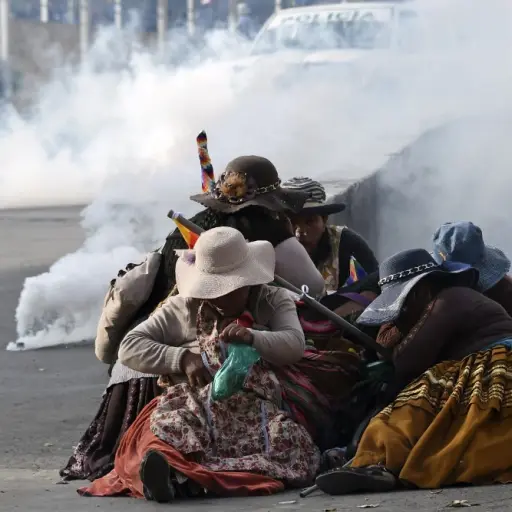 Bolivian indigenous women protect themselves from tear gas during a protest against the interim government in La Paz on November 15, 2019. - Bolivia's interim president Jeanine Anez said Friday that exiled ex-president Evo Morales would have to 