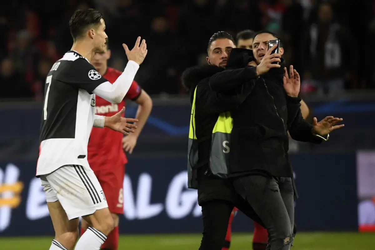 Juventus' Portuguese forward Cristiano Ronaldo (L) argues with a pitch invader after the UEFA Champions League Group D football match between Bayer Leverkusen and Juventus on December 11, 2019 in Leverkusen, western Germany. (Photo by INA FASSBENDER / AFP