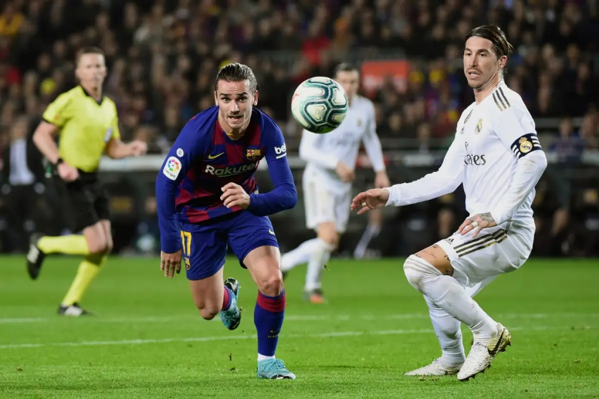 Barcelona's French forward Antoine Griezmann (C) and Real Madrid's Spanish defender Sergio Ramos eye the ball during the "El Clasico" Spanish League football match between Barcelona FC and Real Madrid CF at the Camp Nou Stadium in Barcelona on December 18