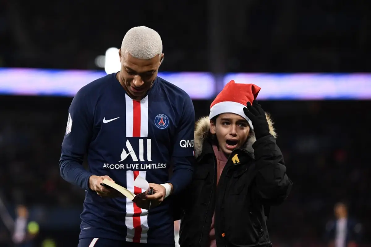 Paris Saint-Germain's French forward Kylian Mbappe (L) signs an autographs during the French L1 football match between Paris Saint-Germain (PSG) and Amiens at the Parc des Princes stadium in Paris on December 21, 2019. (Photo by FRANCK FIFE / AFP)