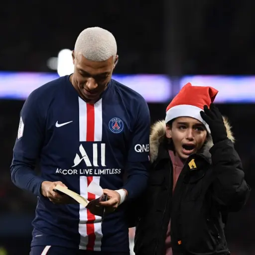 Paris Saint-Germain's French forward Kylian Mbappe (L) signs an autographs during the French L1 football match between Paris Saint-Germain (PSG) and Amiens at the Parc des Princes stadium in Paris on December 21, 2019. (Photo by FRANCK FIFE / AFP)