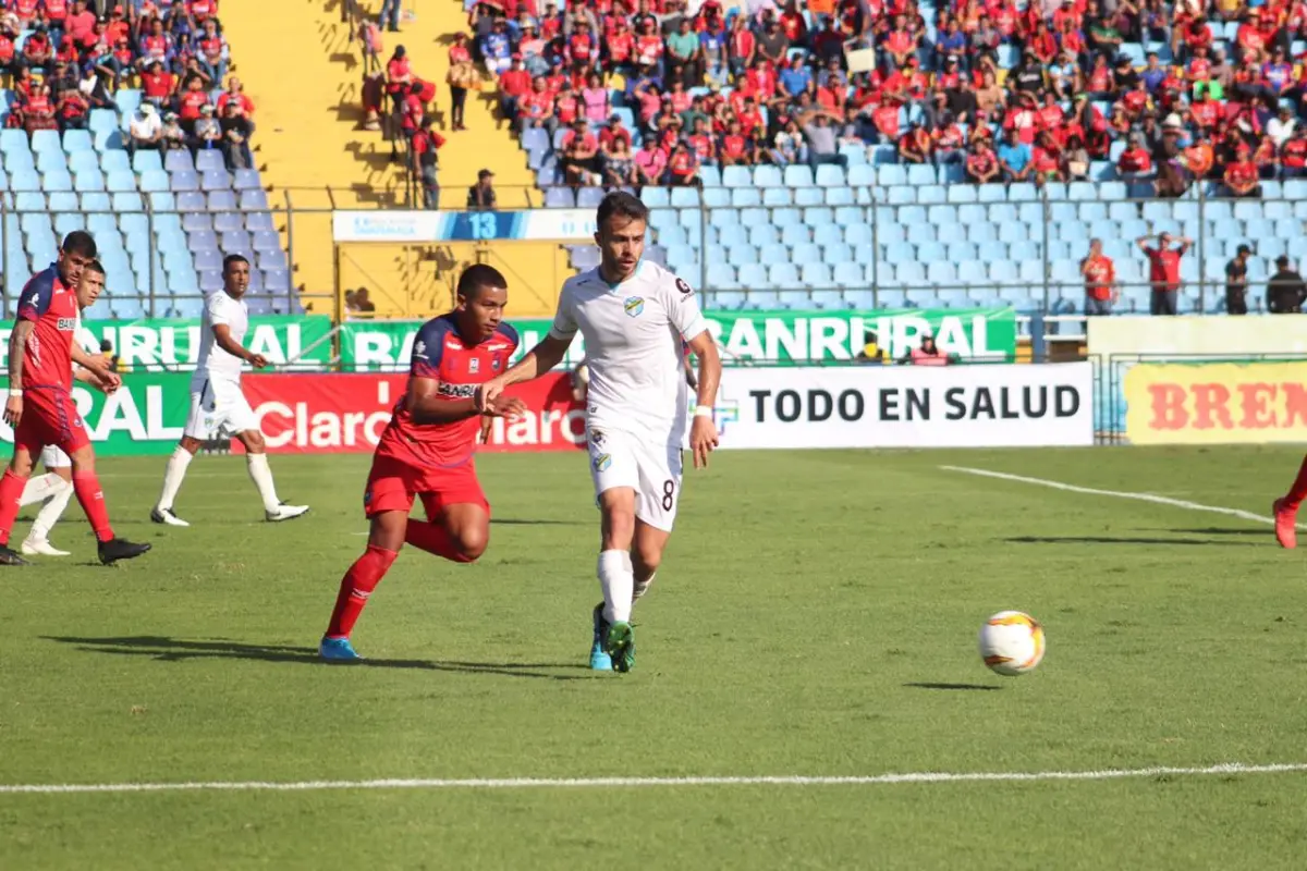 Rodrigo Saravia con posesión del balón ante la presencia de Carlos Alvarado. Foto: AFP