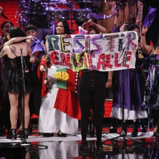 Singers with Chilean artist Mon Laferte show a banner reading 