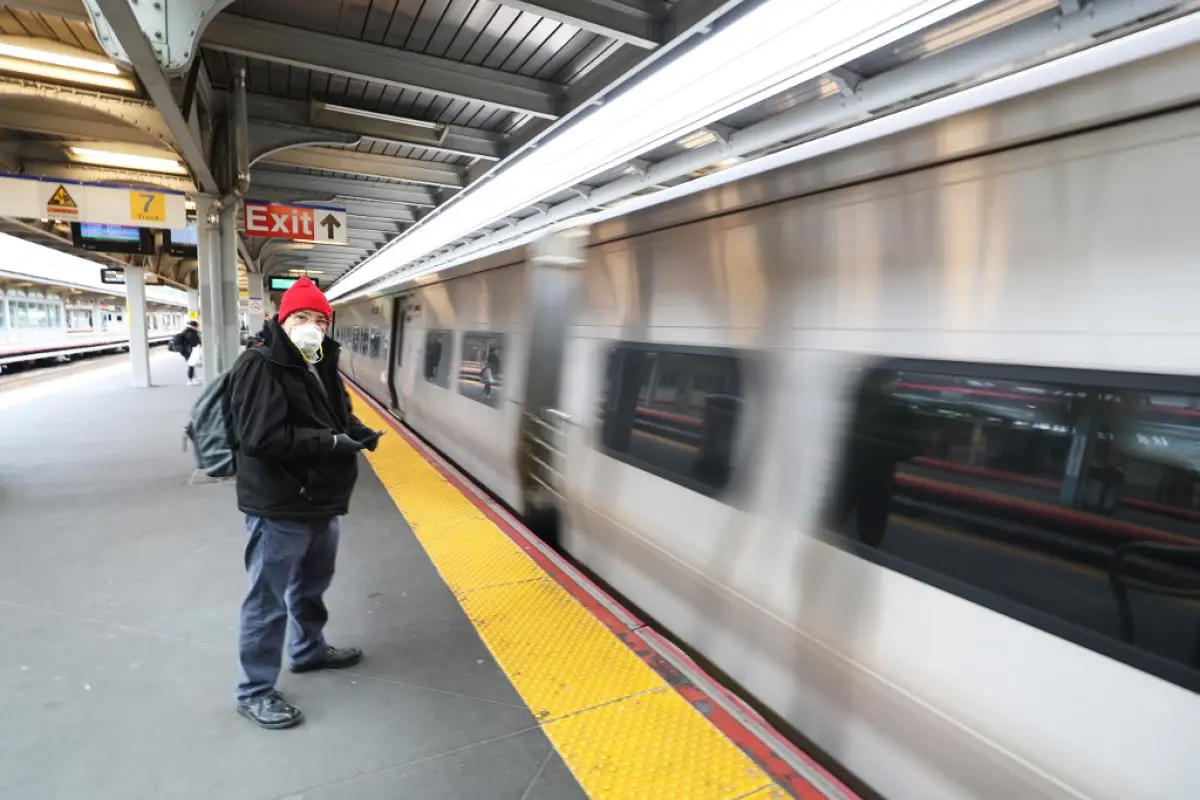 JAMAICA, NEW YORK, - MARCH 18: A man wearing a protective mask waits to board the Long Island Railroad on March 18, 2020 in Jamaica, New York. The World Health Organization declared coronavirus (COVID-19) a global pandemic on March 11th.   Al Bello/Getty 