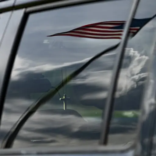 A cross hangs from the rearview mirror of a members car as they listen to Sunday church service held at Great Marsh Park in Cambridge, Maryland, on March 22, 2020. - Pastor Abraham Lankford, who leads Jesus' Church secured the site after concerns over the