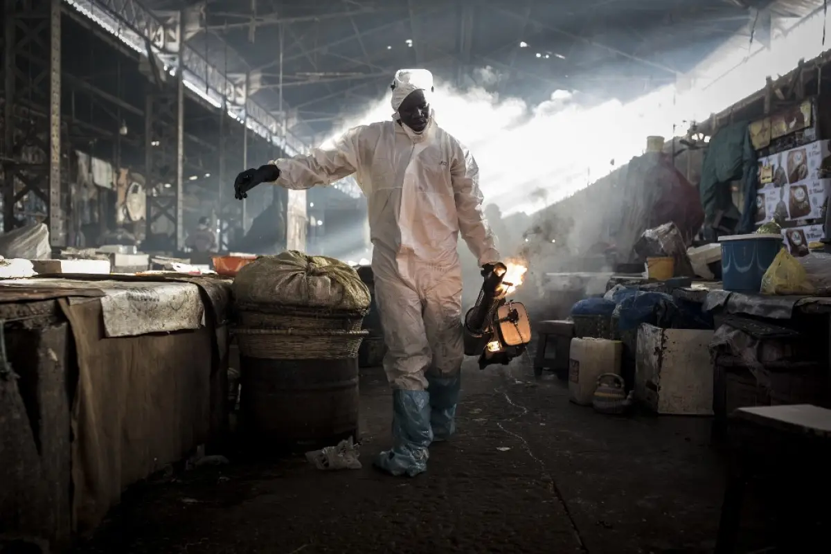 Municipal workers wearing full protective gear as a preventive measure against the COVID-19 Coronavirus carries a sprayer while disinfecting a market in the popular Medina neighbourhood of Dakar on March 22, 2020. - The Senegalese government wanted to be 