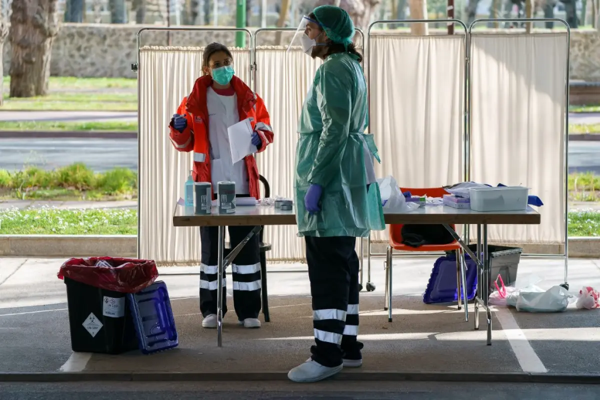 Healthcare workers dressed in protective gear wait for drivers at a drive-through testing point for the COVID-19 disease at the University Hospital in Burgos on March 28, 2020. - The death toll from coronavirus in Spain surged over 5,600 today after a rec