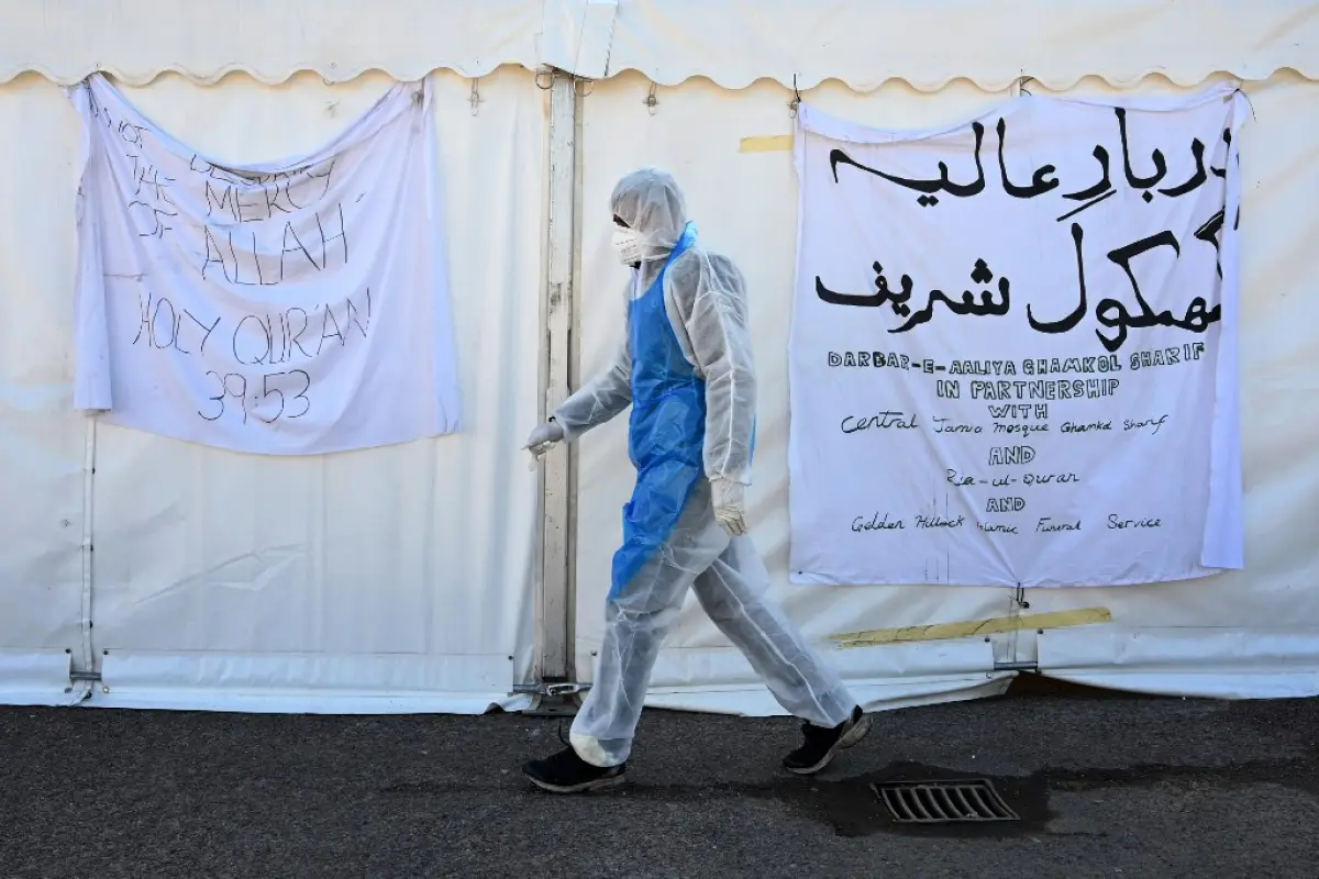 A specially trained volunteer wearing protective clothing works at a temporary mortuary set up in the car park of Central Jamia Mosque Ghamkol Sharif in Birmingham, central England on April 19, 2020, during the novel coronavirus COVID-19 pandemic. - The n