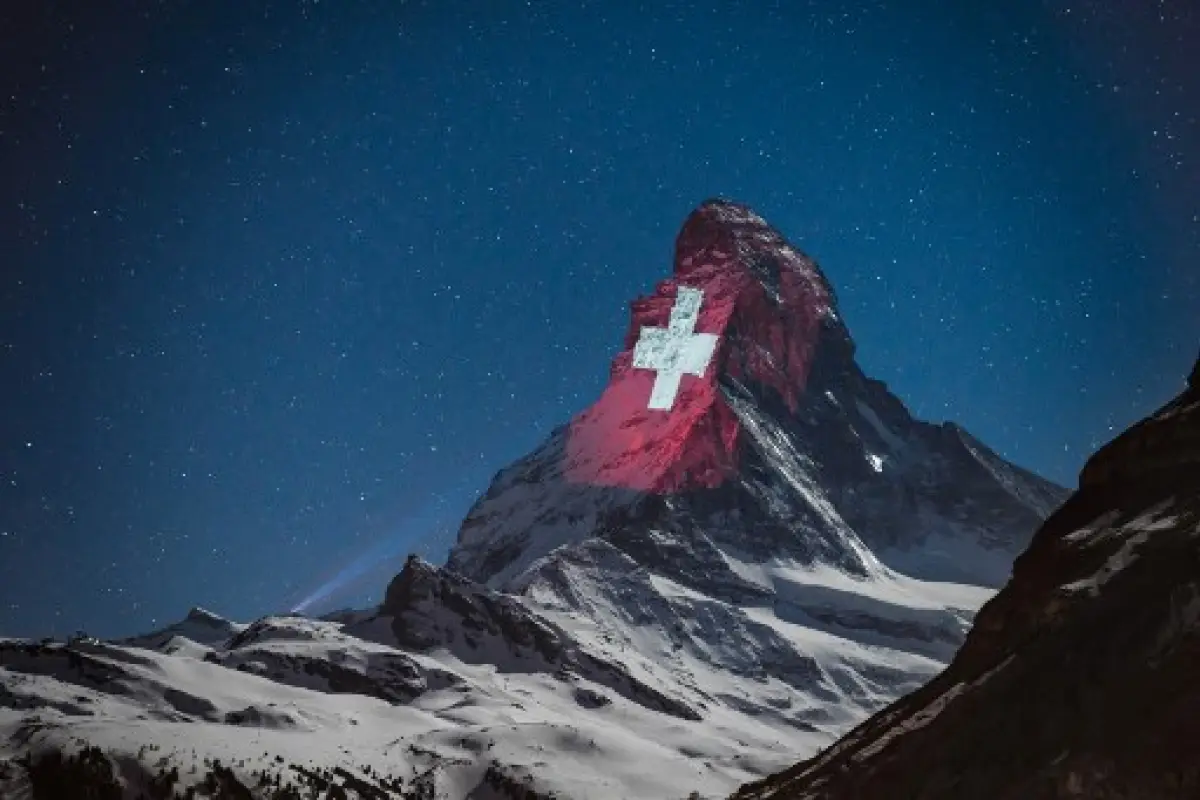 A picture taken late on April 1, 2020 from the Swiss alpine resort of Zermatt shows the Swiss flag on the iconic Matterhorn mountain located on the Italian-Swiss border that peaks at 4478 meters illuminated by Swiss light artist Gerry Hofstetter "with a S