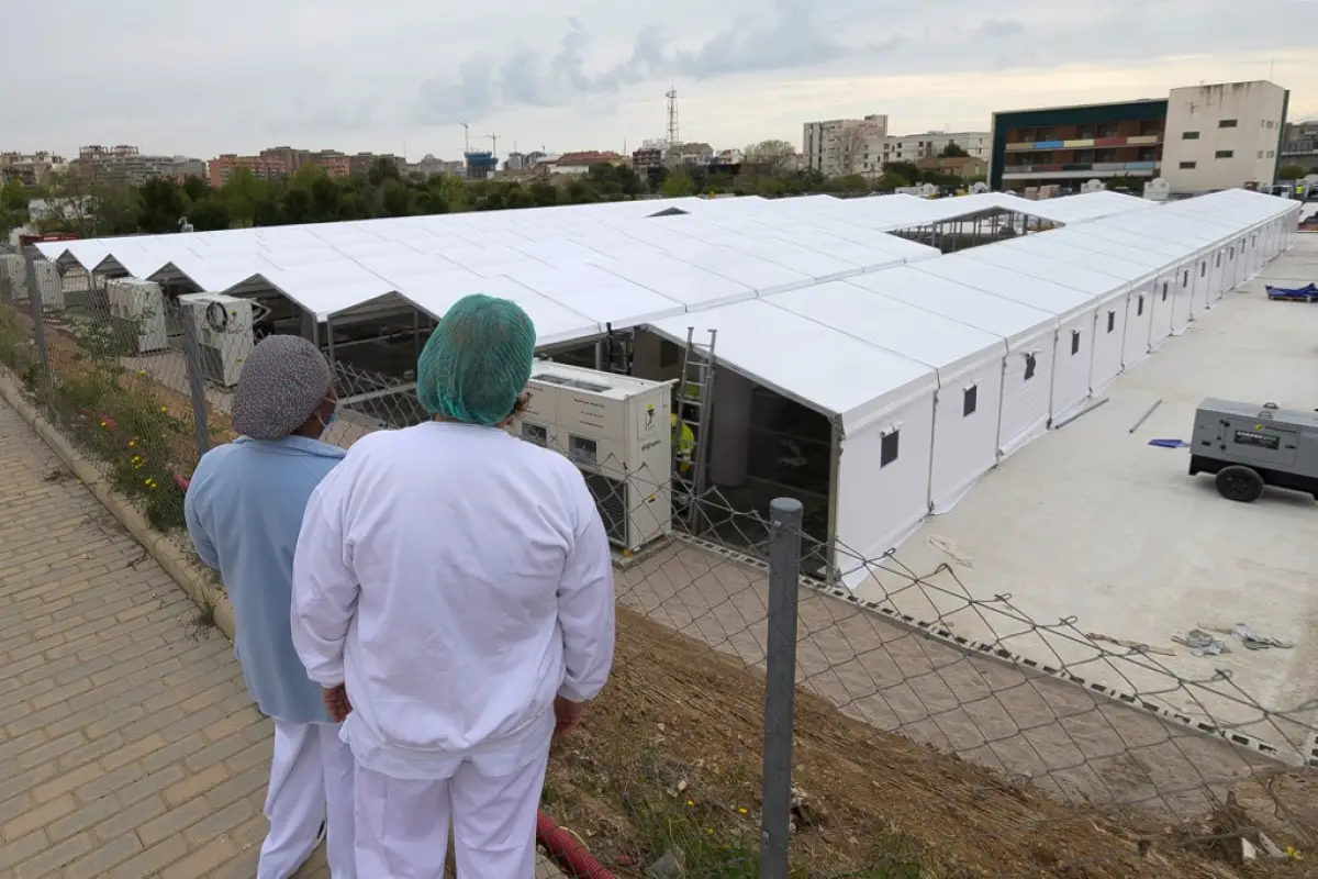 Nurses look at the construction site of a field hospital outside the La Fe Hospital to admit patients suffering from the COVID-19 coronavirus in Valencia on April 5, 2020. - Spain saw its third consecutive daily decline in the number of people dying from 