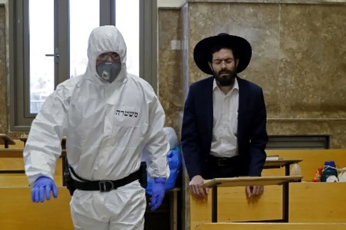 An Israeli police officer, dressed in protective outfit, enters a Yeshiva (Jewish educational institution for studies of traditional religious texts), in the Israeli city of Bei Brak on April 2, 2020, during a control to insure that social distancing meas