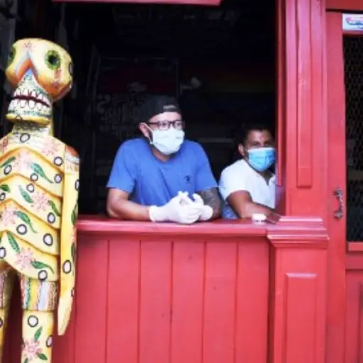Volunteers wait to deliver food to people economically affected by the COVID-19 coronavirus outbreak, at the Rayuela Bar in Guatemala City on April 16, 2020. - In just over a week, the temporary dining room has gone from serving thirty people to prepare o