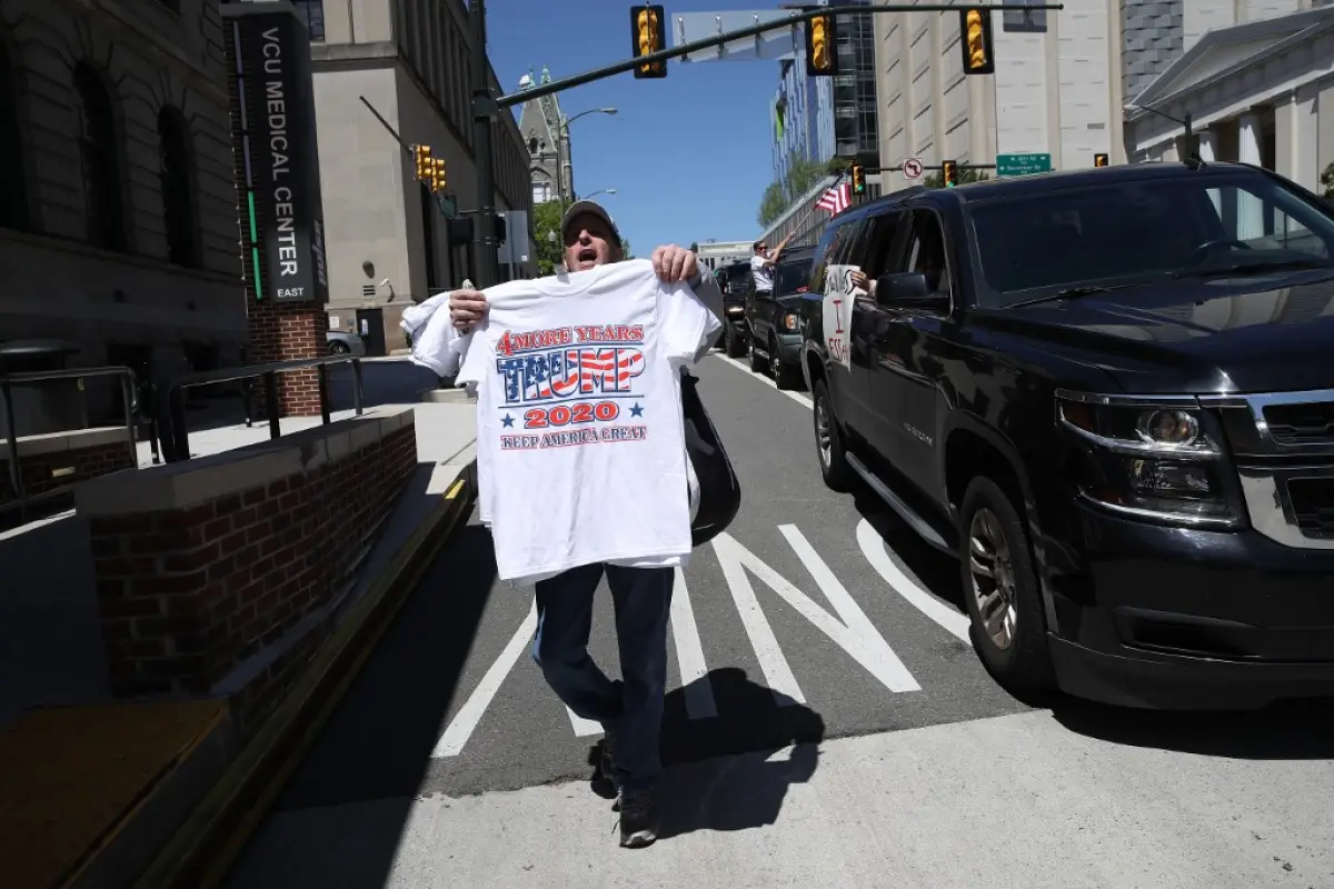 RICHMOND, VIRGINIA - APRIL 22: A man sells t-shirts promoting U.S. President Donald Trump's re-election as protesters attempting to shut down the streets drive near the Virginia State Capitol on April 22, 2020 in Richmond, Virginia. The protesters, who wa