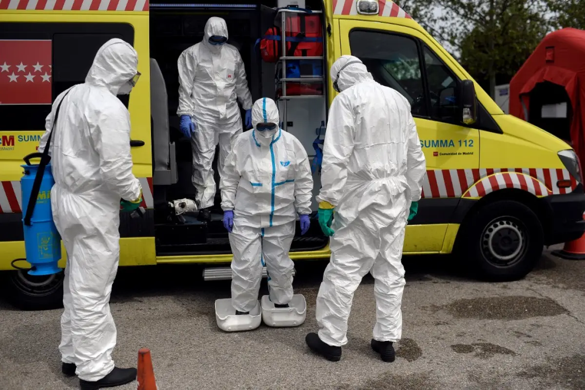 Healthcare workers of the Medical Emergency Services of Madrid (SUMMA 112) UVI-6 unit wearing protective suits arrive to get disinfected by firefighters at IFEMA in Madrid on April 19, 2020. - Spain imposed a tight lockdown on March 14 to slow the spread 