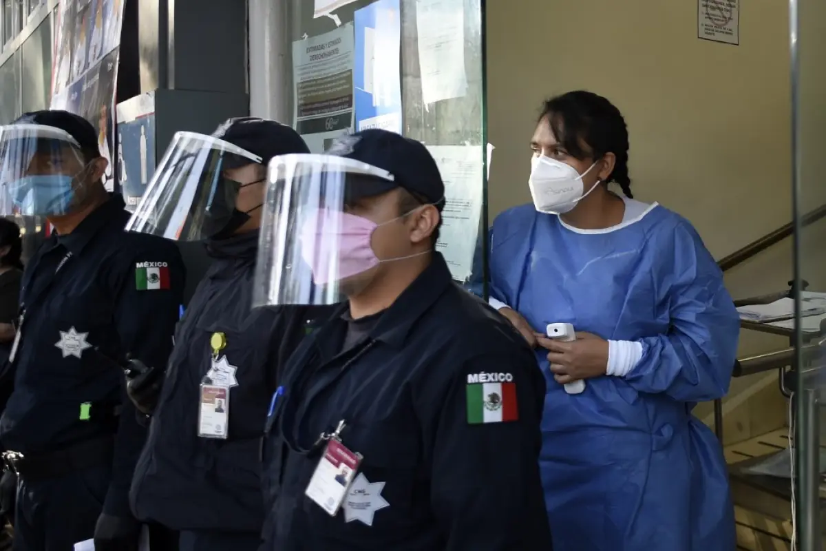 A health worker of the Tacuba General Hospital looks at colleagues demonstrating for the lack of medical material to care for COVID-9 patients next to policemen wearing face masks and shields in Mexico City on April 21, 2020. (Photo by Alfredo ESTRELLA / 