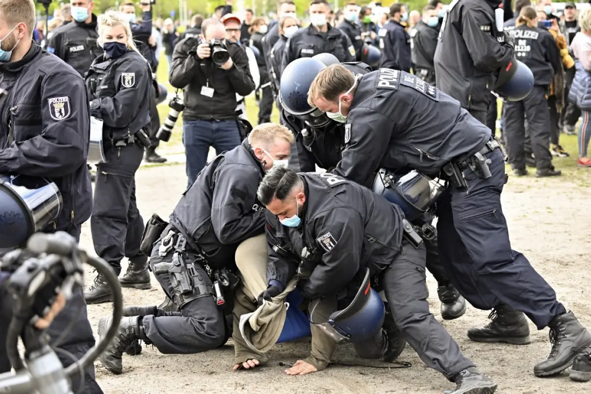 Police arrest a man who attended a protest against restrictions implemented in order to limit the spread of the novel coronavirus / COVID-19 pandemic, on May 16, 2020 near the Chancellery (background) in Berlin. - From anger over lockdown measures to a pu