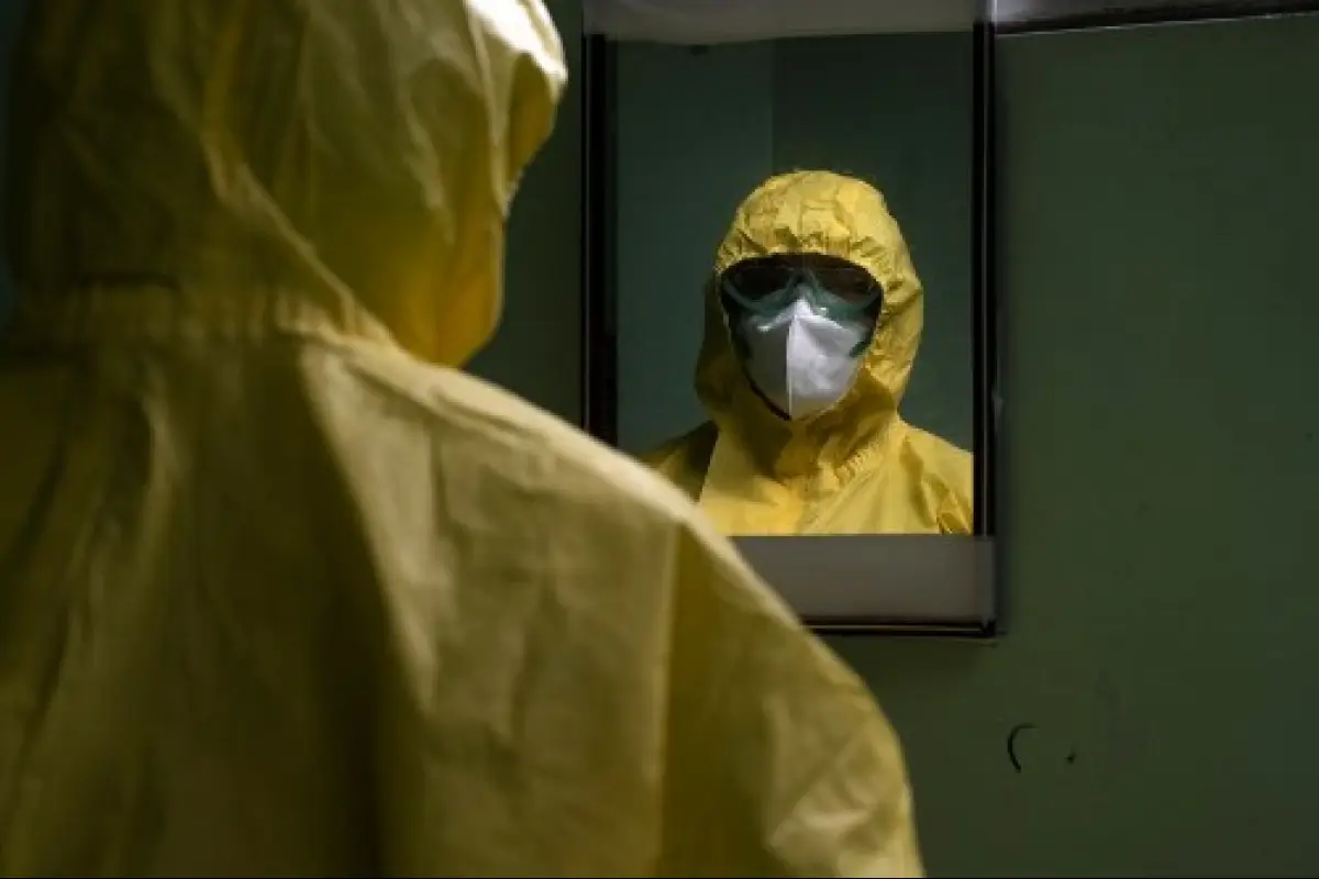 An intensivist nurse looks herself in the mirror as she fixes her level III biosafety suit before tending to patients infected with the novel coronavirus, COVID-19, in the intensive care unit of the San Rafael Hospital in Santa Tecla, La Libertad, just 10