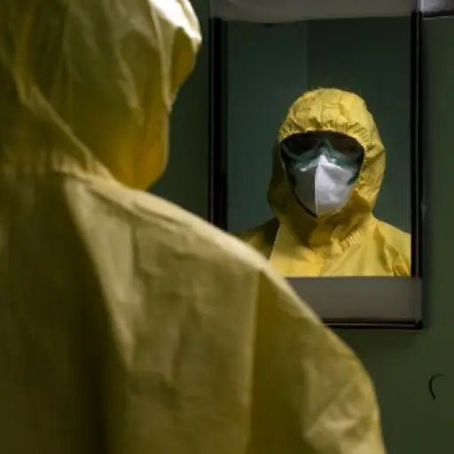 An intensivist nurse looks herself in the mirror as she fixes her level III biosafety suit before tending to patients infected with the novel coronavirus, COVID-19, in the intensive care unit of the San Rafael Hospital in Santa Tecla, La Libertad, just 10