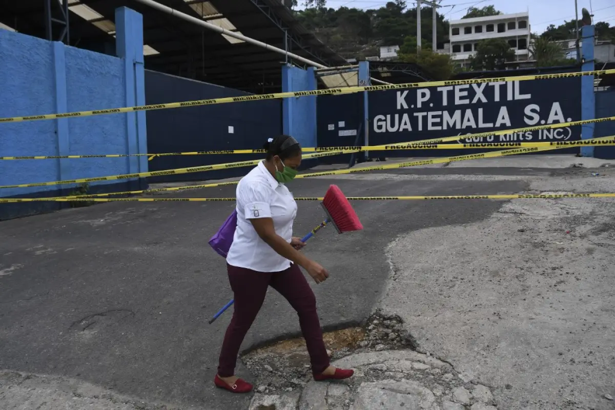 A woman wearing a face mask walks past a closed textile factory after 24 of its employees tested positive for the new coronavirus, COVID-19, in San Miguel Petapa, 30 km south of Guatemala City, on May 18, 2020. (Photo by Johan ORDONEZ / AFP)