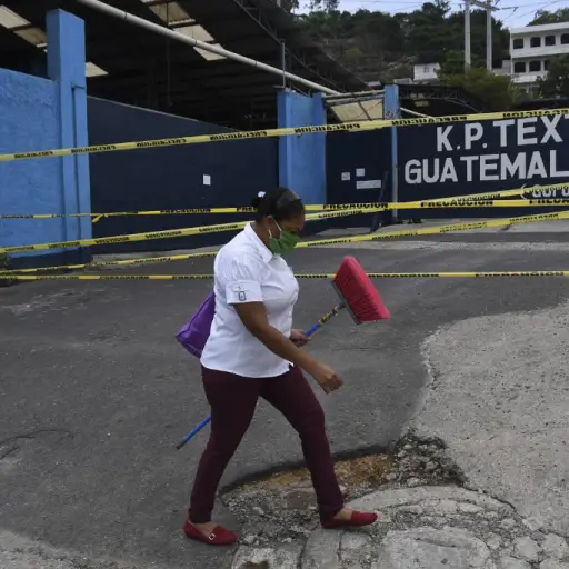 A woman wearing a face mask walks past a closed textile factory after 24 of its employees tested positive for the new coronavirus, COVID-19, in San Miguel Petapa, 30 km south of Guatemala City, on May 18, 2020. (Photo by Johan ORDONEZ / AFP)