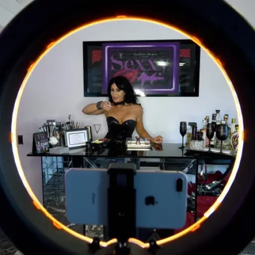 LAS VEGAS, NEVADA - MAY 06: Entertainer Jennifer Romas, shown through a ring light, records a tutorial at her home showing how to make a specialty drink from her topless revue 