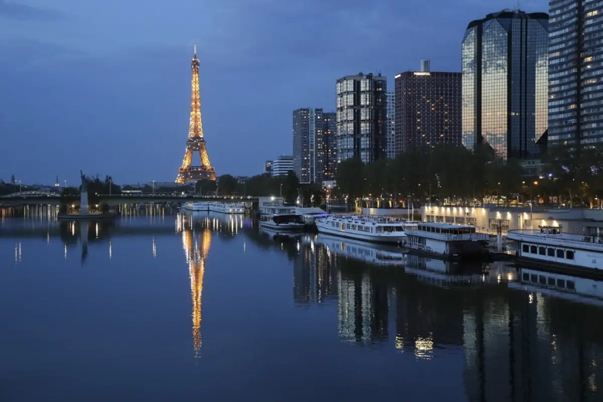 General view of the illuminated Eiffel Tower reflected on the Seine river in Paris at night, on April 12, 2020, during a strict lockdown in France to stop the spread of COVID-19 (novel coronavirus). (Photo by Ludovic MARIN / AFP)