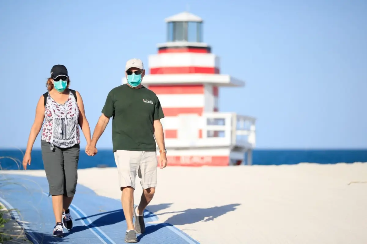 MIAMI BEACH, FLORIDA - APRIL 29: A couple walks from the closed beach in South Pointe Park on April 29, 2020 in Miami Beach, Florida. The city of Miami Beach partially reopened parks and facilities including golf courses, tennis courts and marinas as it b