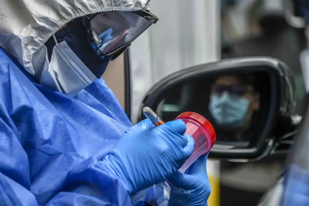 A nurse prepares the sample bottle before taking a sample of a driver at a COVID-19 drive-through test point, in Bogota on May 14, 2020. - Latin America and the Caribbean exceeded 400,000 confirmed cases of the new coronavirus on Thursday, which has alrea