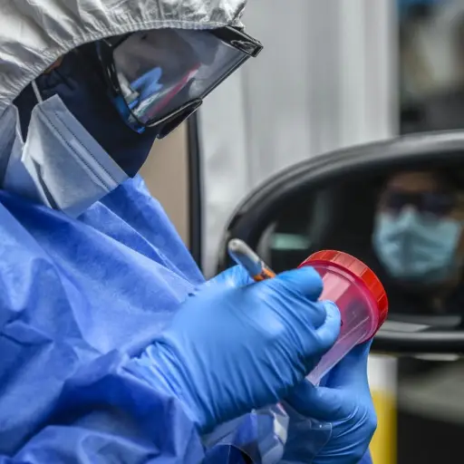 A nurse prepares the sample bottle before taking a sample of a driver at a COVID-19 drive-through test point, in Bogota on May 14, 2020. - Latin America and the Caribbean exceeded 400,000 confirmed cases of the new coronavirus on Thursday, which has alrea