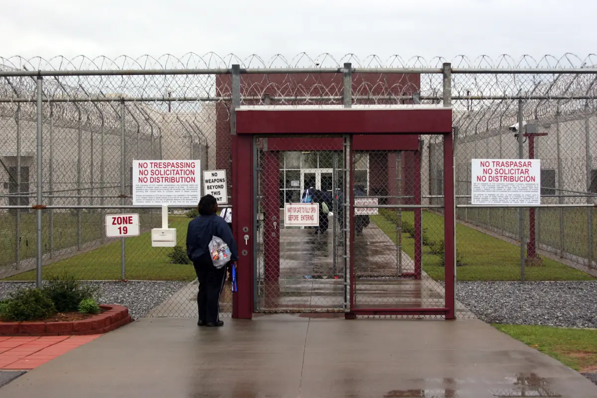 This April 13, 2009 photo shows an employee of Immigration and Customs Enforcement's Stewart Detention Center in Lumpkin, Ga., waiting for the front gate to be opened so she can enter. The all-male detention center with a capacity of 1,924 detainees is op