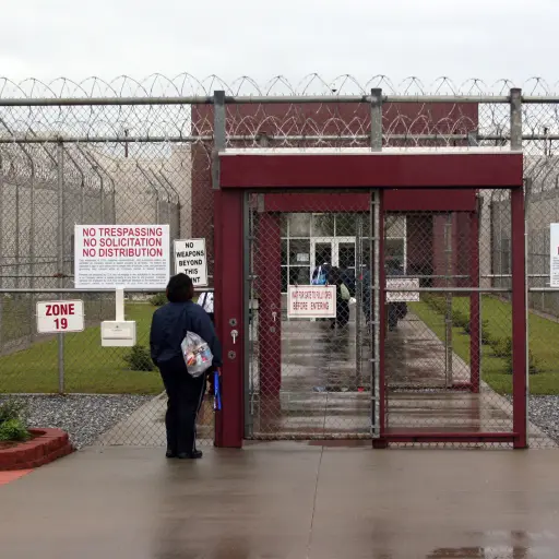 This April 13, 2009 photo shows an employee of Immigration and Customs Enforcement's Stewart Detention Center in Lumpkin, Ga., waiting for the front gate to be opened so she can enter. The all-male detention center with a capacity of 1,924 detainees is op