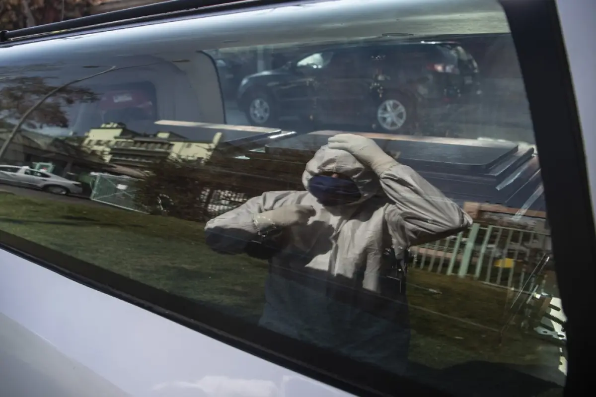 An employee of a funeral home is reflected on a funeral car's window as he arranges his security gear while waiting outside the San Jose public hospital morgue, amid the spread of the coronavirus disease (COVID-19) in Santiago, on June 05, 2020. - Deaths 