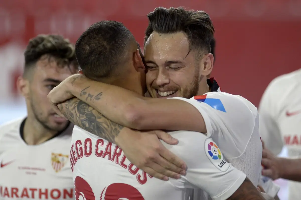 Sevilla's Argentinian midfielder Lucas Ocampos (R) celebrates with teammates after scoring a goal during the Spanish League football match between Sevilla FC and Real Betis at the Ramon Sanchez Pizjuan stadium in Seville on June 11, 2020. (Photo by CRISTI