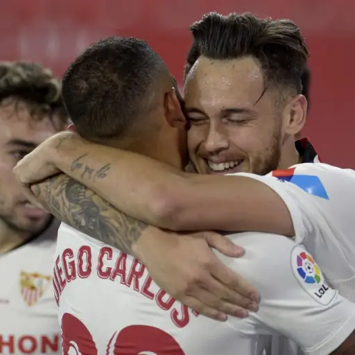 Sevilla's Argentinian midfielder Lucas Ocampos (R) celebrates with teammates after scoring a goal during the Spanish League football match between Sevilla FC and Real Betis at the Ramon Sanchez Pizjuan stadium in Seville on June 11, 2020. (Photo by CRISTI
