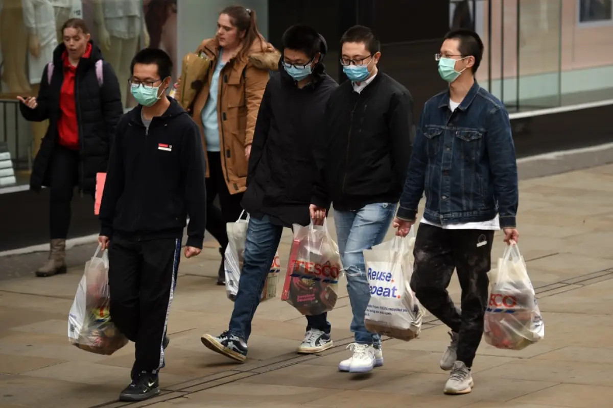 Shoppers wearing a protective facemasks walk through central Manchester on June 5, 2020, as lockdown measures are eased during the novel coronavirus COVID-19 pandemic. - Face coverings will soon be compulsory for people wanting to travel on public transpo