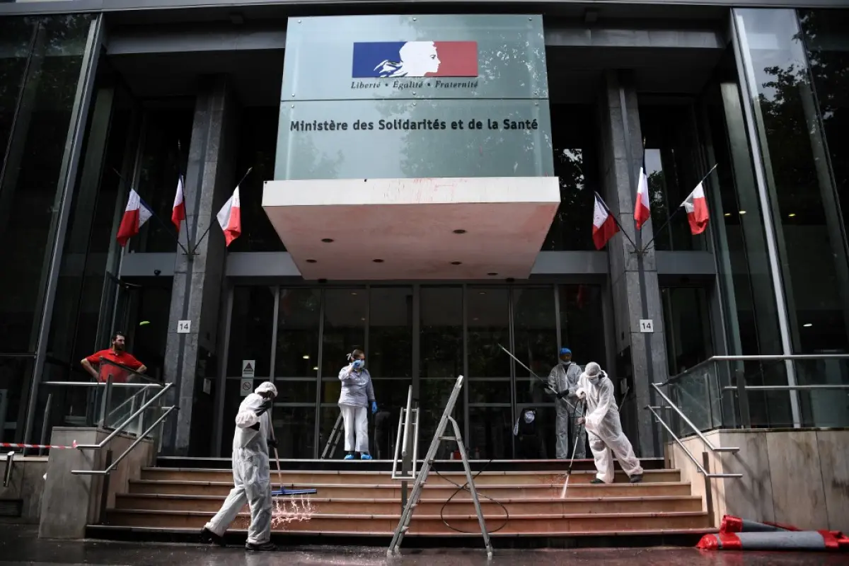 Employers clean the entrance of the  French Health Ministry soiled by red paint after French activists of Attac stage a protest in support of medical workers outside the Ministry in Paris on June 20, 2020. (Photo by Anne-Christine POUJOULAT / AFP)