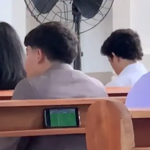 Finge poner atención al sermón del padre, pero lo cachan viendo el Mundial ,