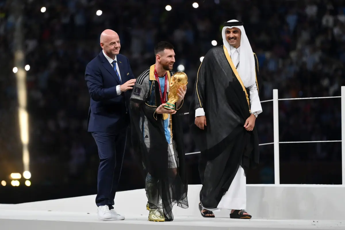LUSAIL CITY, QATAR - DECEMBER 18: Lionel Messi of Argentina kisses the FIFA World Cup Qatar 2022 Winner's Trophy as Gianni Infantino, President of FIFA, and Sheikh Tamim bin Hamad Al Thani, Emir of Qatar, look on during the FIFA World Cup Qatar 2022 Final