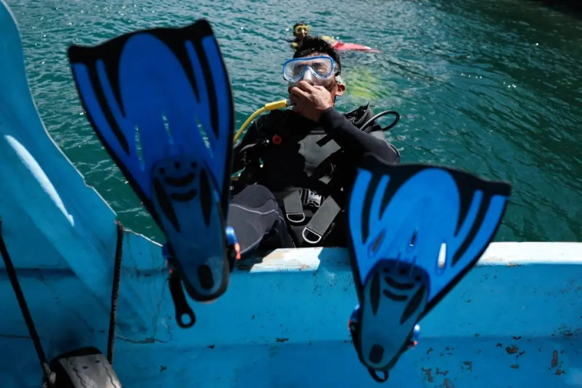 Un buzo se lanza para recolectar desechos durante una jornada de limpieza en el lago Atitlán. Foto: EFE